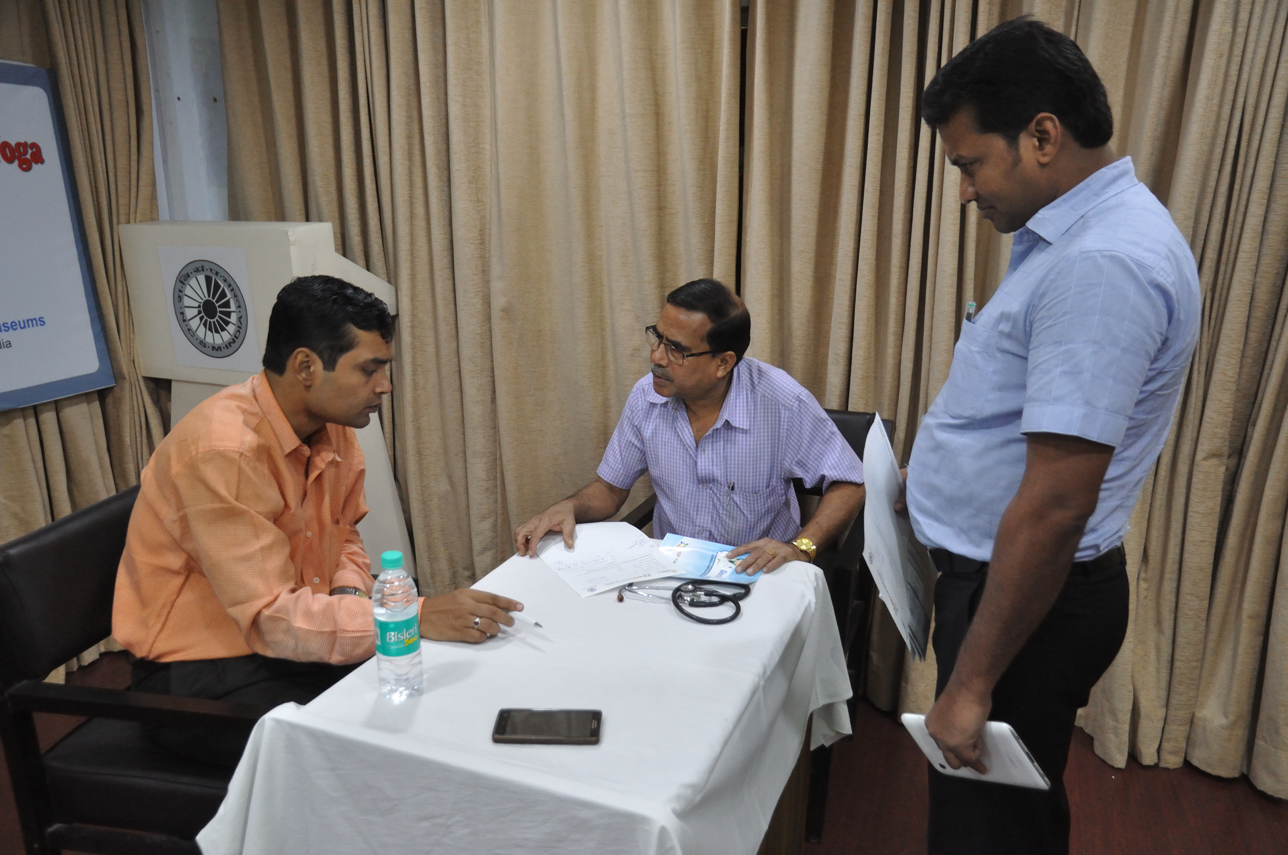 Doctor conducting health checkup for Indian workers at plant welfare desk
